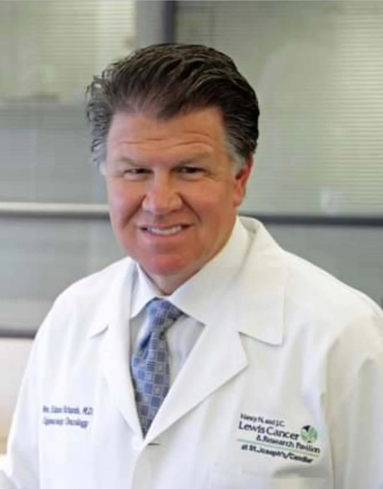 A man in a white jacket smiling