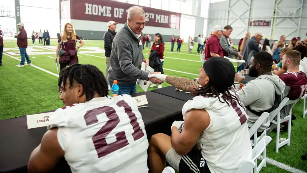 football players at table shaking hands with people